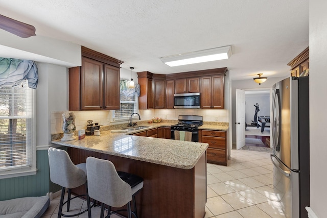 kitchen featuring pendant lighting, kitchen peninsula, sink, and appliances with stainless steel finishes