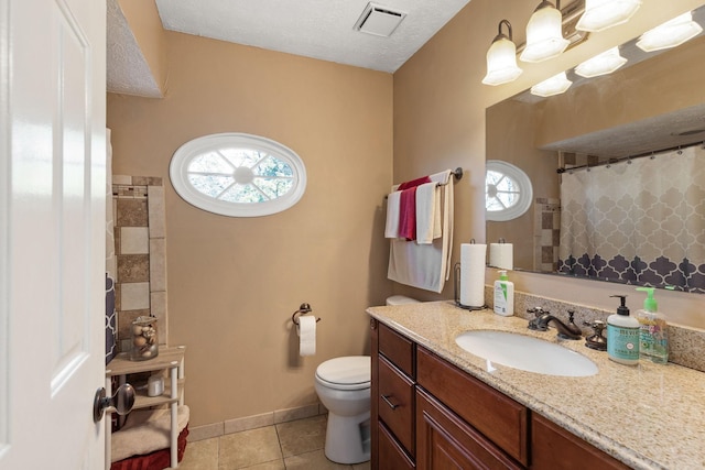 bathroom with tile patterned flooring, vanity, a healthy amount of sunlight, and toilet