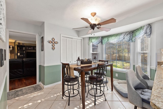 tiled dining area with a textured ceiling and ceiling fan