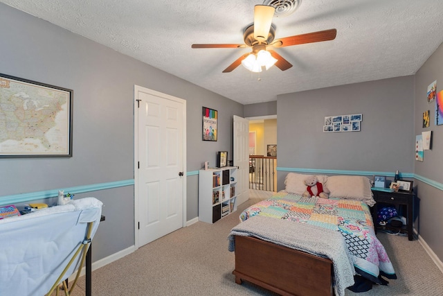 carpeted bedroom featuring ceiling fan and a textured ceiling