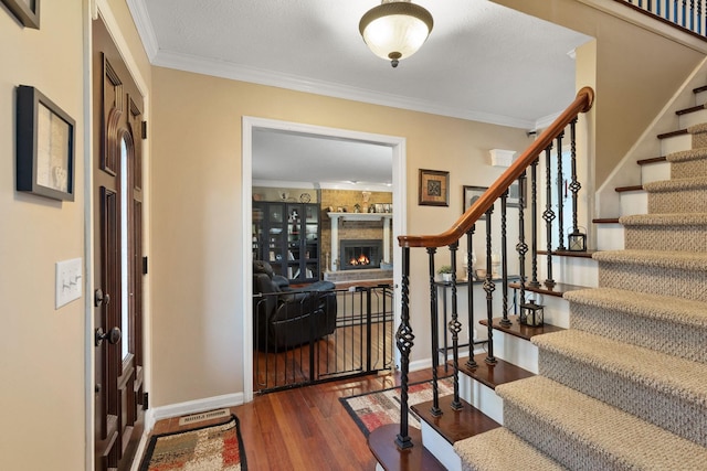 entrance foyer featuring a large fireplace, dark hardwood / wood-style flooring, and ornamental molding