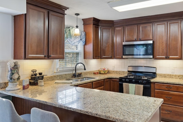 kitchen with pendant lighting, sink, gas stove, a kitchen bar, and kitchen peninsula