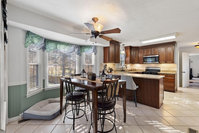 tiled dining space featuring a textured ceiling, ceiling fan, and sink