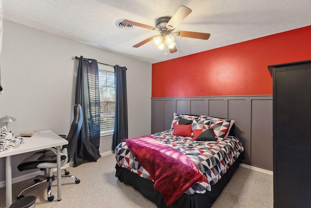 carpeted bedroom featuring ceiling fan and a textured ceiling