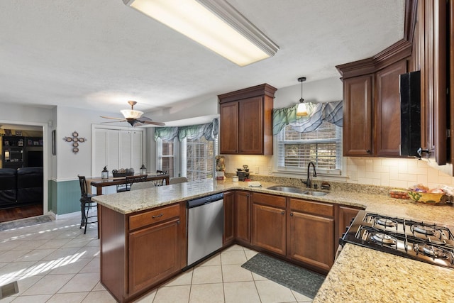 kitchen featuring dishwasher, sink, kitchen peninsula, decorative light fixtures, and light tile patterned floors