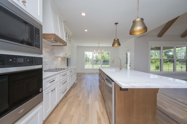 kitchen with a large island with sink, white cabinetry, and appliances with stainless steel finishes