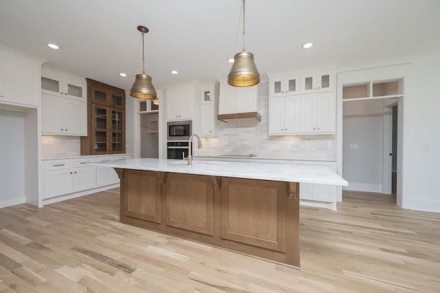 kitchen with white cabinetry, built in microwave, sink, and a spacious island