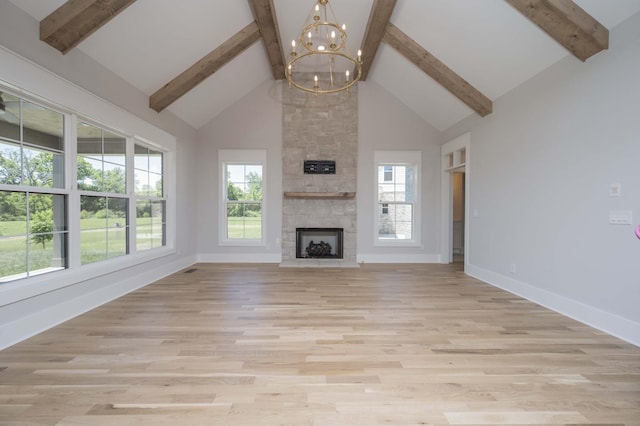 unfurnished living room featuring a fireplace, an inviting chandelier, high vaulted ceiling, and plenty of natural light