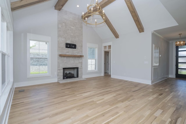 unfurnished living room featuring beamed ceiling, a stone fireplace, high vaulted ceiling, and a chandelier