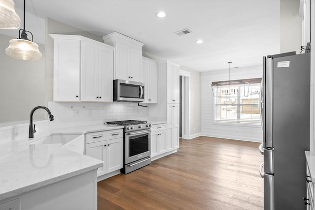 kitchen with sink, white cabinets, hanging light fixtures, and appliances with stainless steel finishes