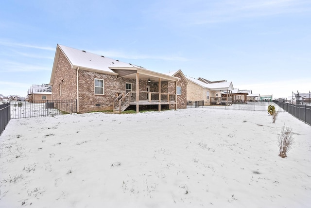 snow covered back of property with ceiling fan