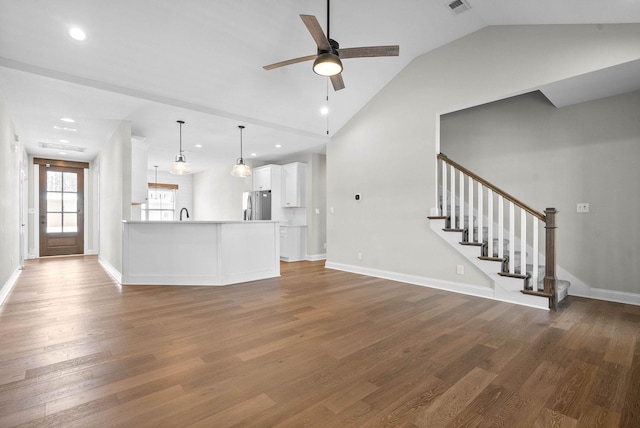 unfurnished living room featuring hardwood / wood-style floors, vaulted ceiling, and ceiling fan