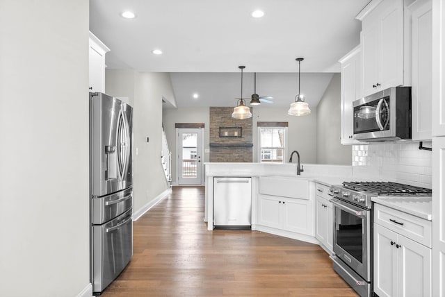 kitchen with backsplash, pendant lighting, white cabinetry, and stainless steel appliances