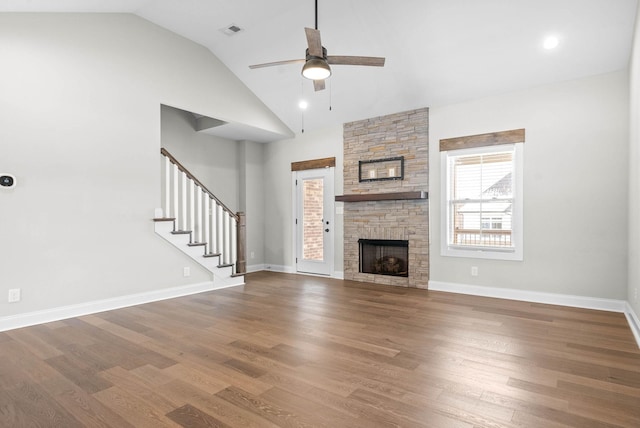 unfurnished living room with a stone fireplace, ceiling fan, hardwood / wood-style floors, and lofted ceiling