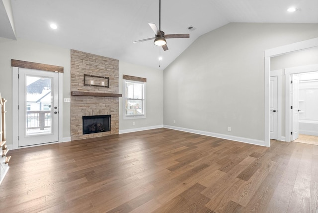 unfurnished living room with wood-type flooring, a stone fireplace, plenty of natural light, and ceiling fan