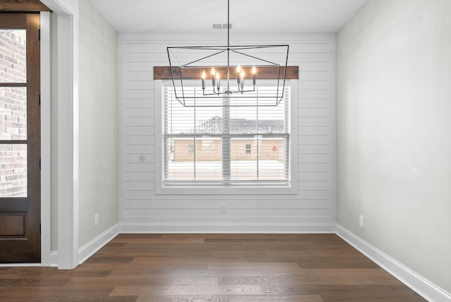 unfurnished dining area featuring dark hardwood / wood-style flooring and an inviting chandelier