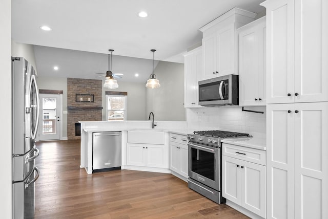 kitchen with white cabinets, ceiling fan, appliances with stainless steel finishes, decorative light fixtures, and kitchen peninsula