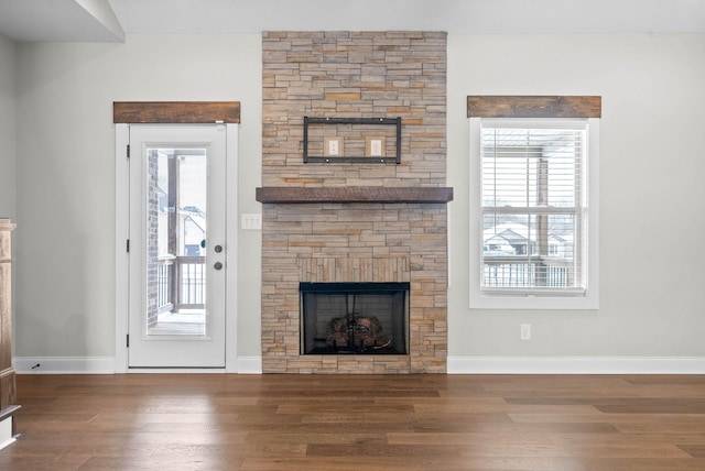 unfurnished living room with a stone fireplace, a wealth of natural light, and hardwood / wood-style flooring