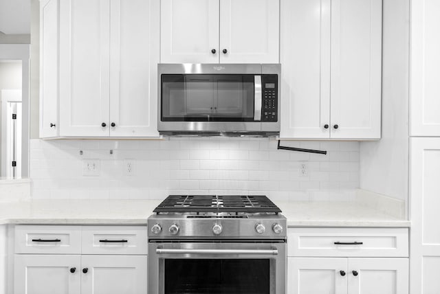 kitchen featuring white cabinets, appliances with stainless steel finishes, and tasteful backsplash