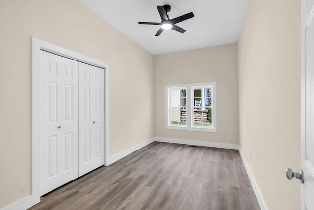 unfurnished bedroom with ceiling fan, light wood-type flooring, and a closet