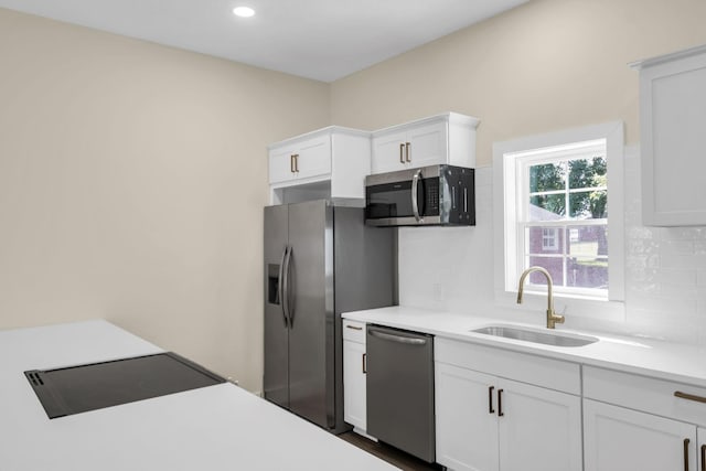 kitchen with appliances with stainless steel finishes, backsplash, white cabinetry, and sink