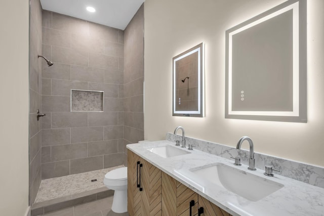 bathroom featuring tile patterned floors, vanity, toilet, and tiled shower