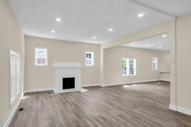 unfurnished living room with light wood-type flooring and a brick fireplace