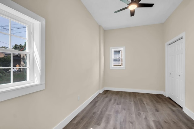 unfurnished bedroom with multiple windows, ceiling fan, a closet, and wood-type flooring