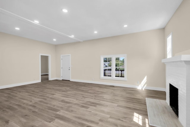 unfurnished living room featuring light hardwood / wood-style floors and a brick fireplace