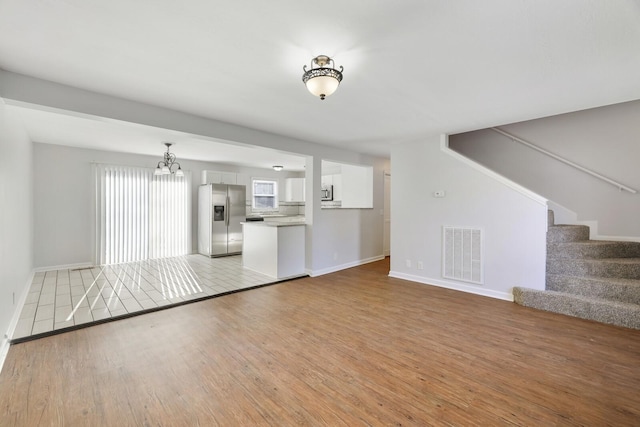 unfurnished living room featuring light hardwood / wood-style flooring and an inviting chandelier