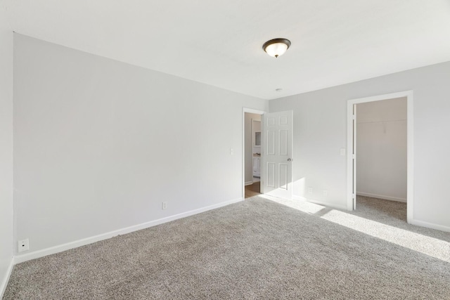 unfurnished bedroom with carpet, a spacious closet, and a closet