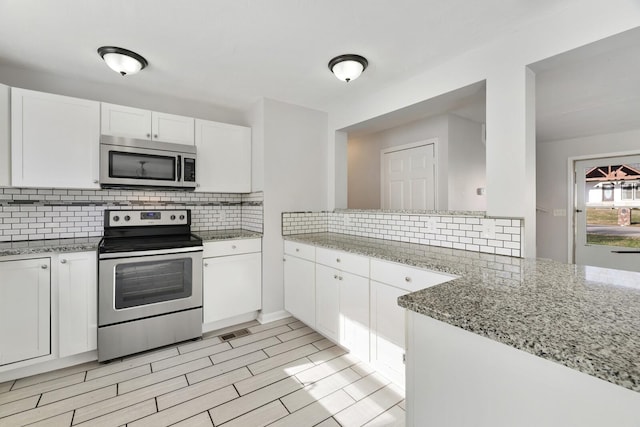 kitchen featuring white cabinetry, tasteful backsplash, light stone counters, kitchen peninsula, and appliances with stainless steel finishes