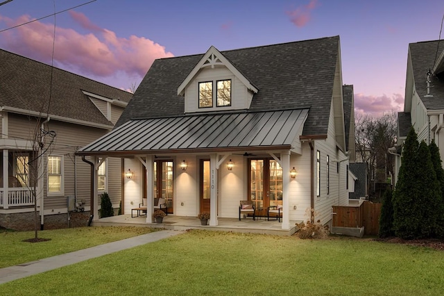 back house at dusk featuring a lawn