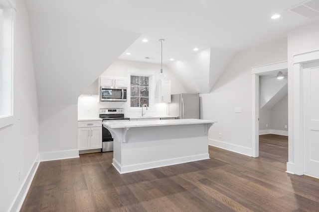 kitchen with white cabinetry, stainless steel appliances, pendant lighting, a breakfast bar area, and a kitchen island