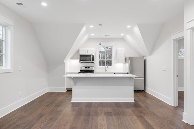 kitchen featuring white cabinetry, pendant lighting, vaulted ceiling, a kitchen island, and appliances with stainless steel finishes