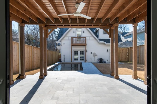 view of patio featuring a balcony, ceiling fan, and a fenced in pool