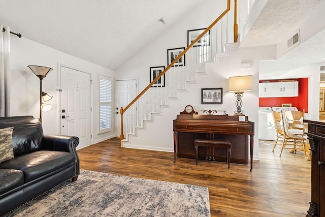 living room featuring dark hardwood / wood-style flooring, high vaulted ceiling, and washing machine and clothes dryer