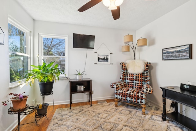 living area featuring ceiling fan, a textured ceiling, and hardwood / wood-style flooring