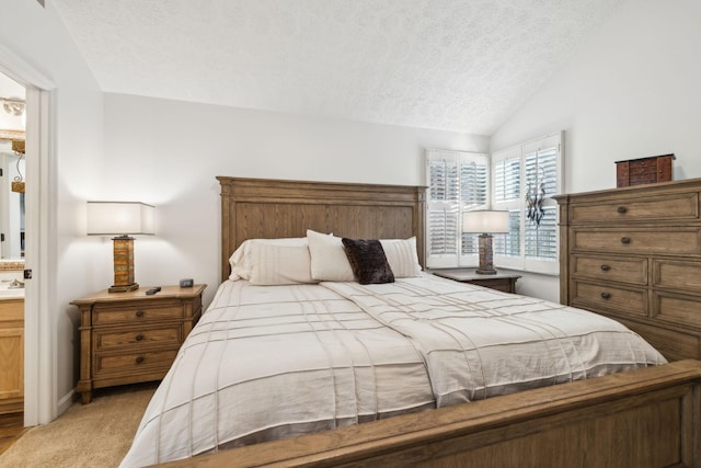 carpeted bedroom with a textured ceiling, ensuite bathroom, and vaulted ceiling