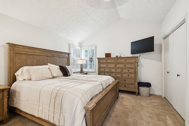 carpeted bedroom featuring lofted ceiling, a textured ceiling, and a closet