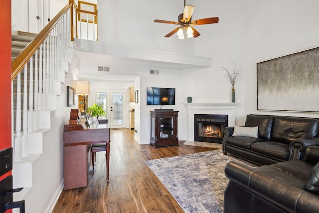 living room with ceiling fan, a towering ceiling, dark wood-type flooring, and french doors