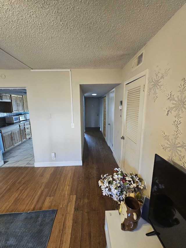 hall featuring wood-type flooring and a textured ceiling