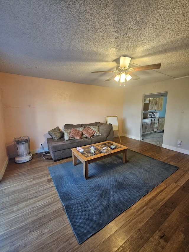 living room featuring wood-type flooring, a textured ceiling, and ceiling fan