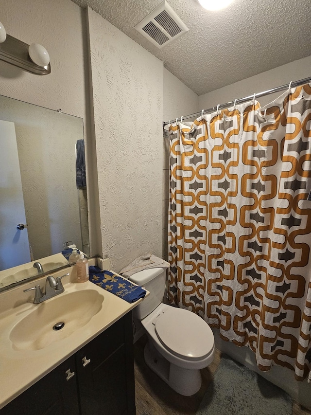 bathroom with a shower with curtain, vanity, toilet, and a textured ceiling