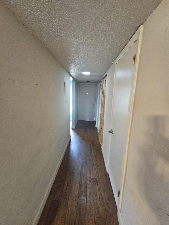 hallway featuring dark wood-type flooring and a textured ceiling