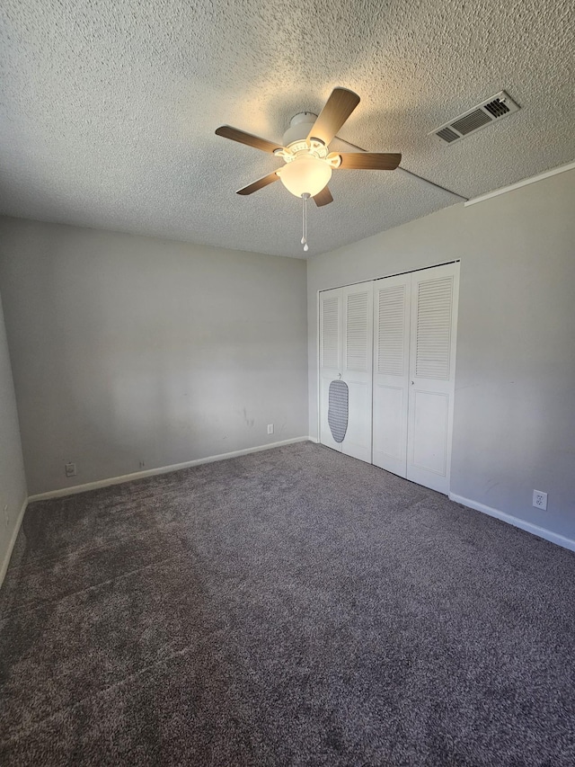 unfurnished bedroom featuring ceiling fan, a closet, dark carpet, and a textured ceiling