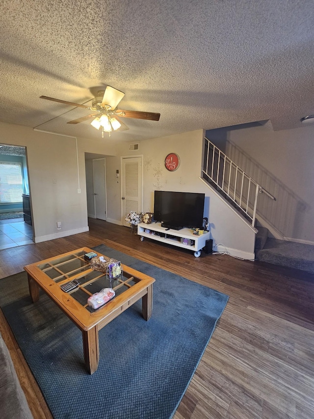 living room with hardwood / wood-style flooring, ceiling fan, and a textured ceiling