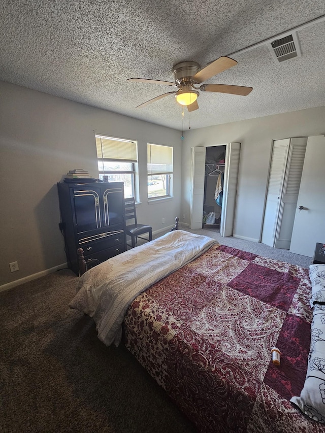 carpeted bedroom with a textured ceiling, ceiling fan, and multiple closets