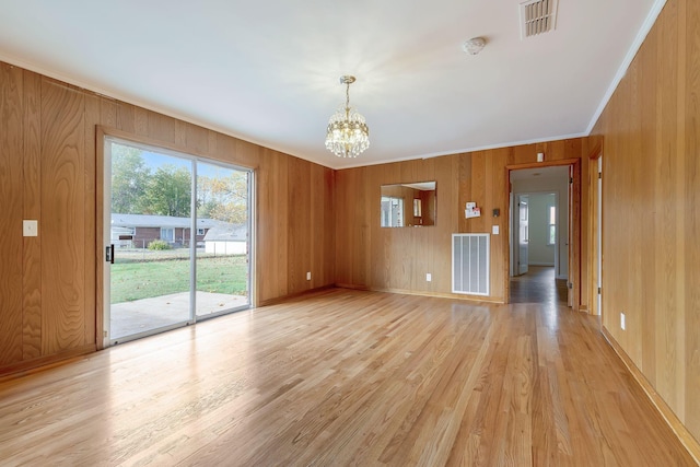 interior space featuring wood walls, a notable chandelier, light hardwood / wood-style floors, and ornamental molding