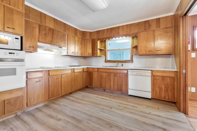 kitchen featuring sink, tasteful backsplash, crown molding, light hardwood / wood-style floors, and white appliances